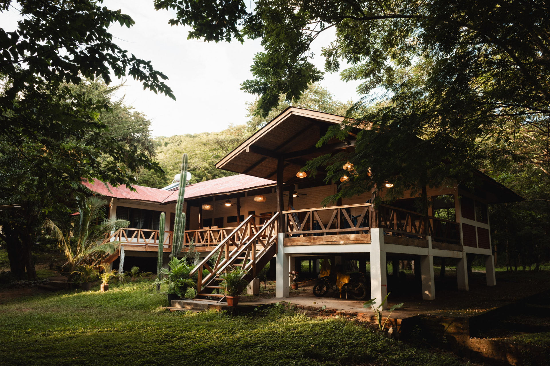 Raised tropical buildings at Sanctuary on the Beach with wooden decks, red roofs and surrounding trees