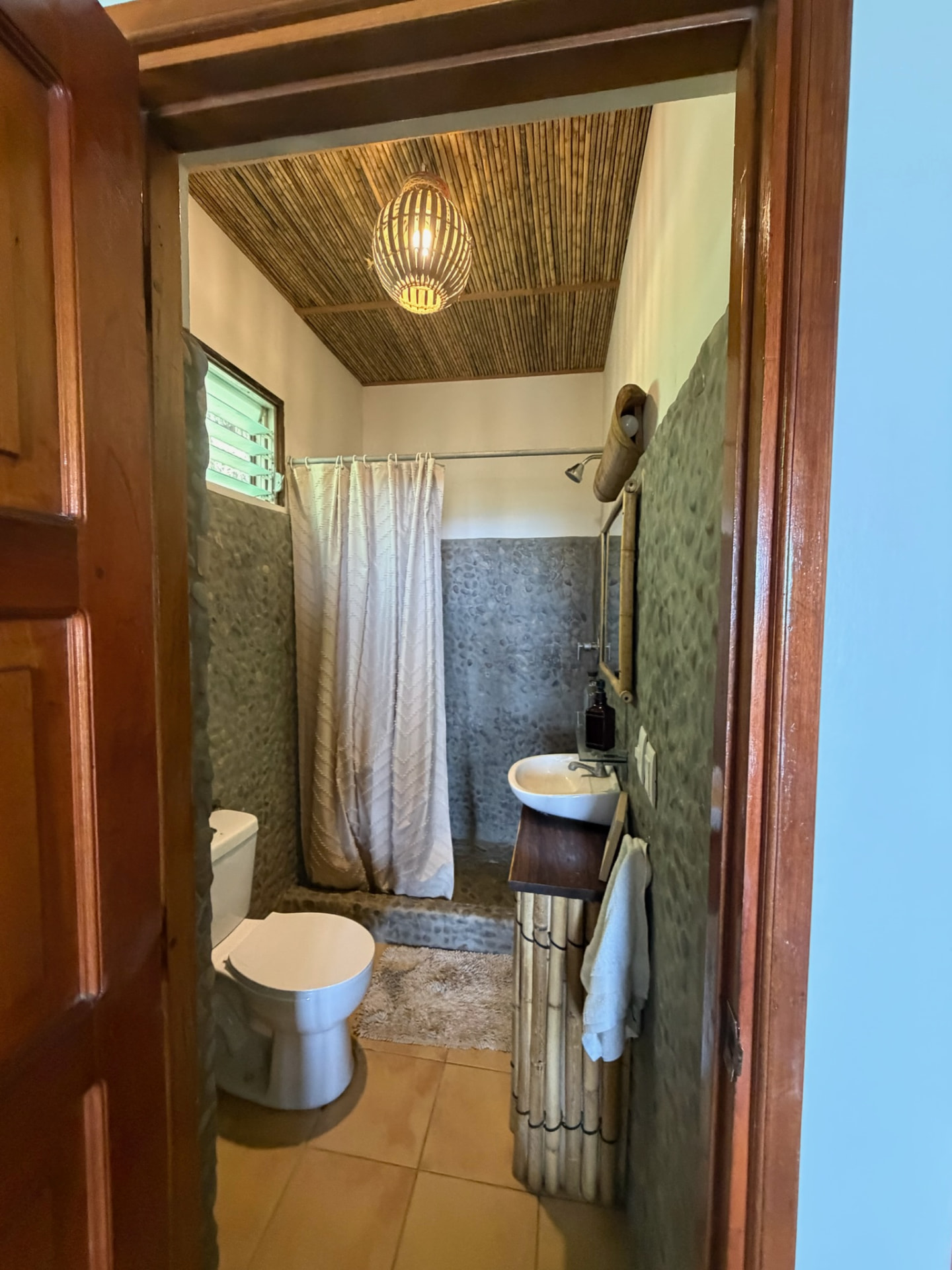 Bathroom with river-stone walls, bamboo details and a walk-in shower