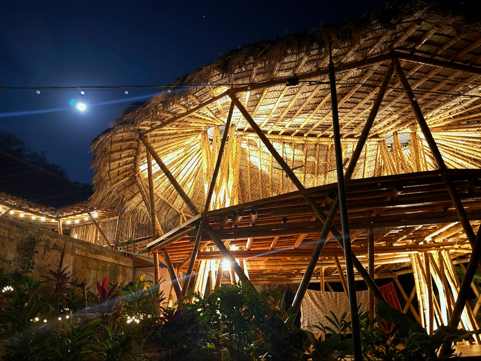 Bamboo gathering structure illuminated warmly beneath the night sky