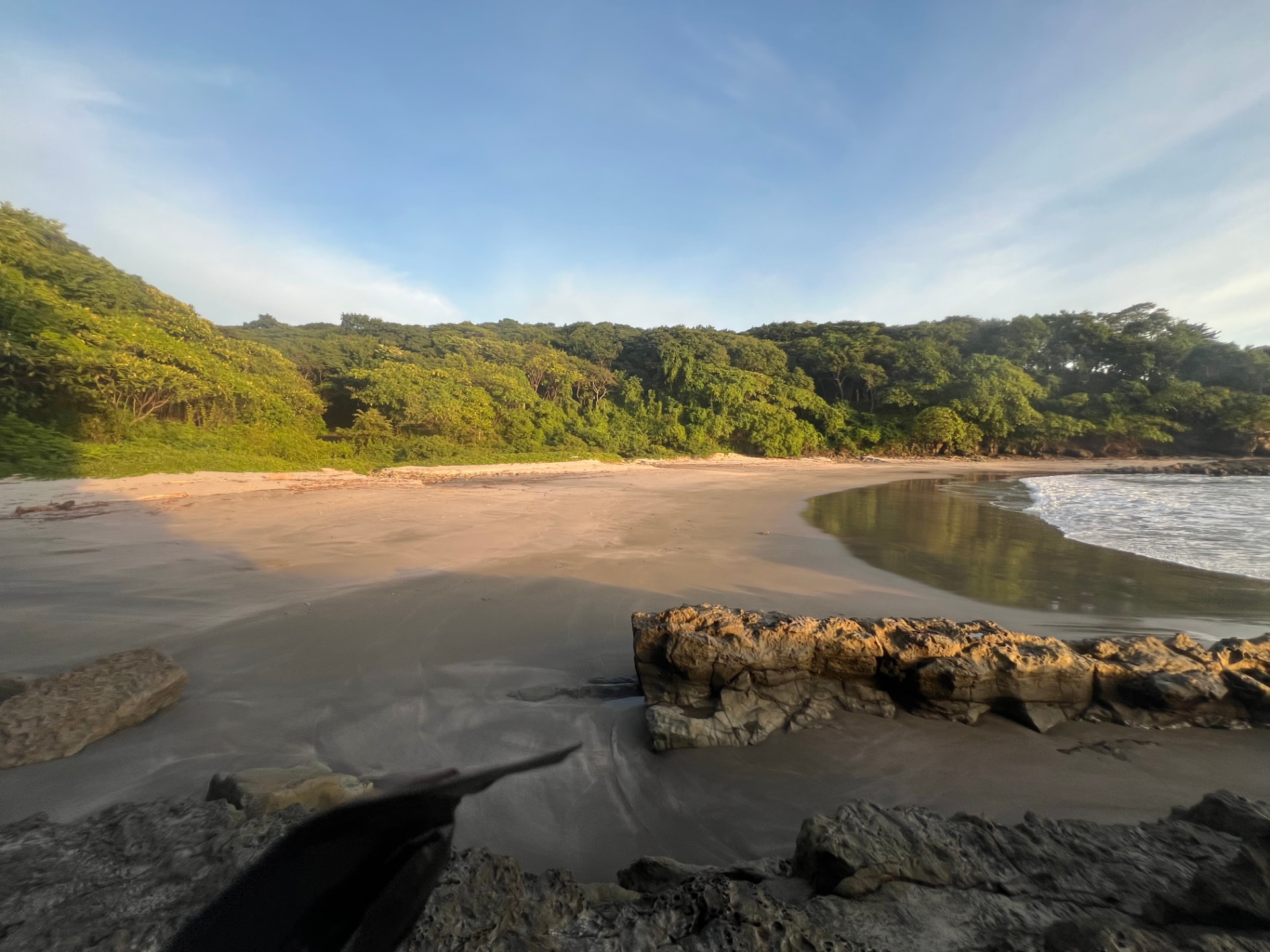 A sweeping Playa El Coco beach edged by jungle and sunlit rocks