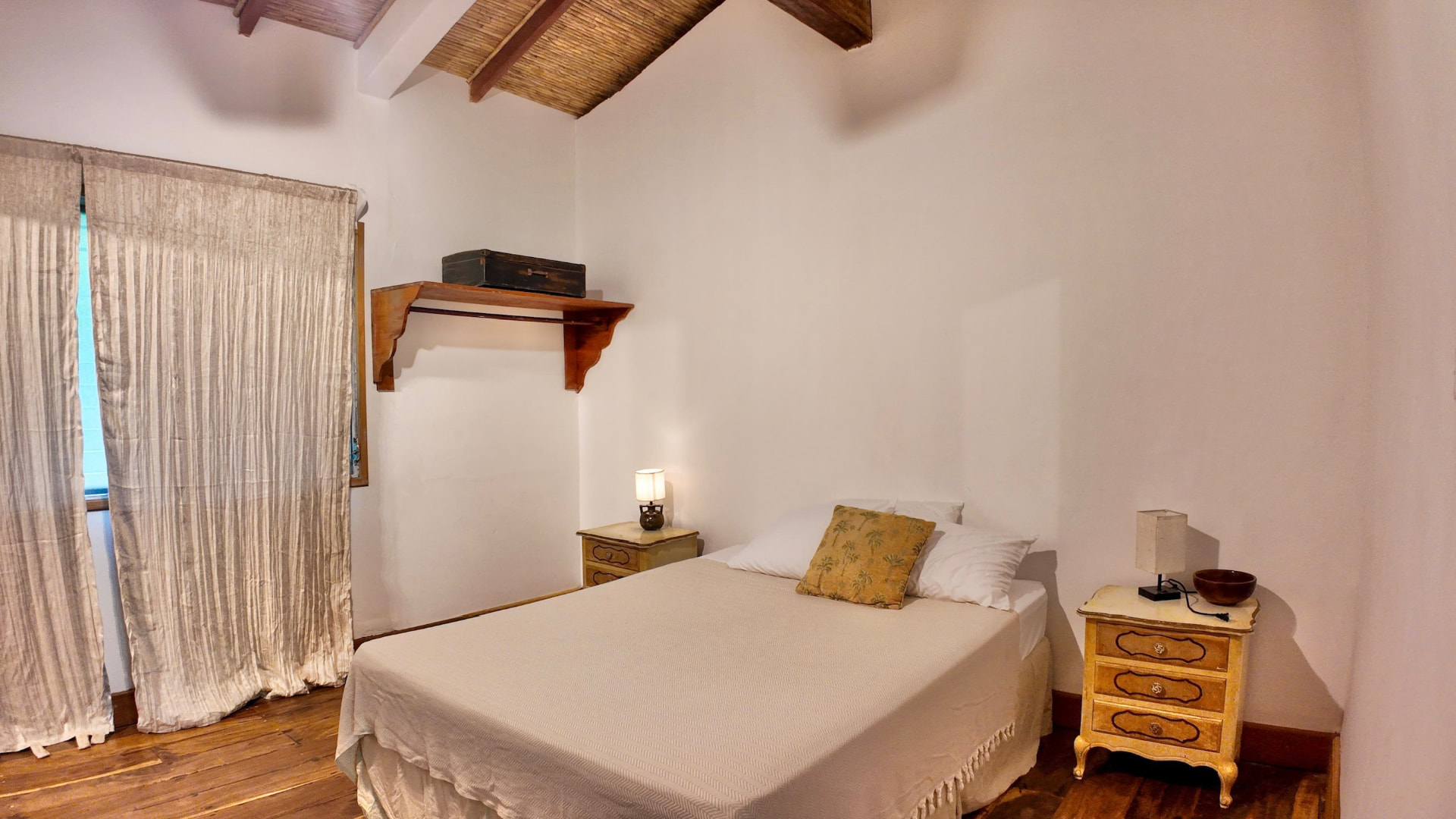 A bright room with a double bed, bedside tables and wooden floor