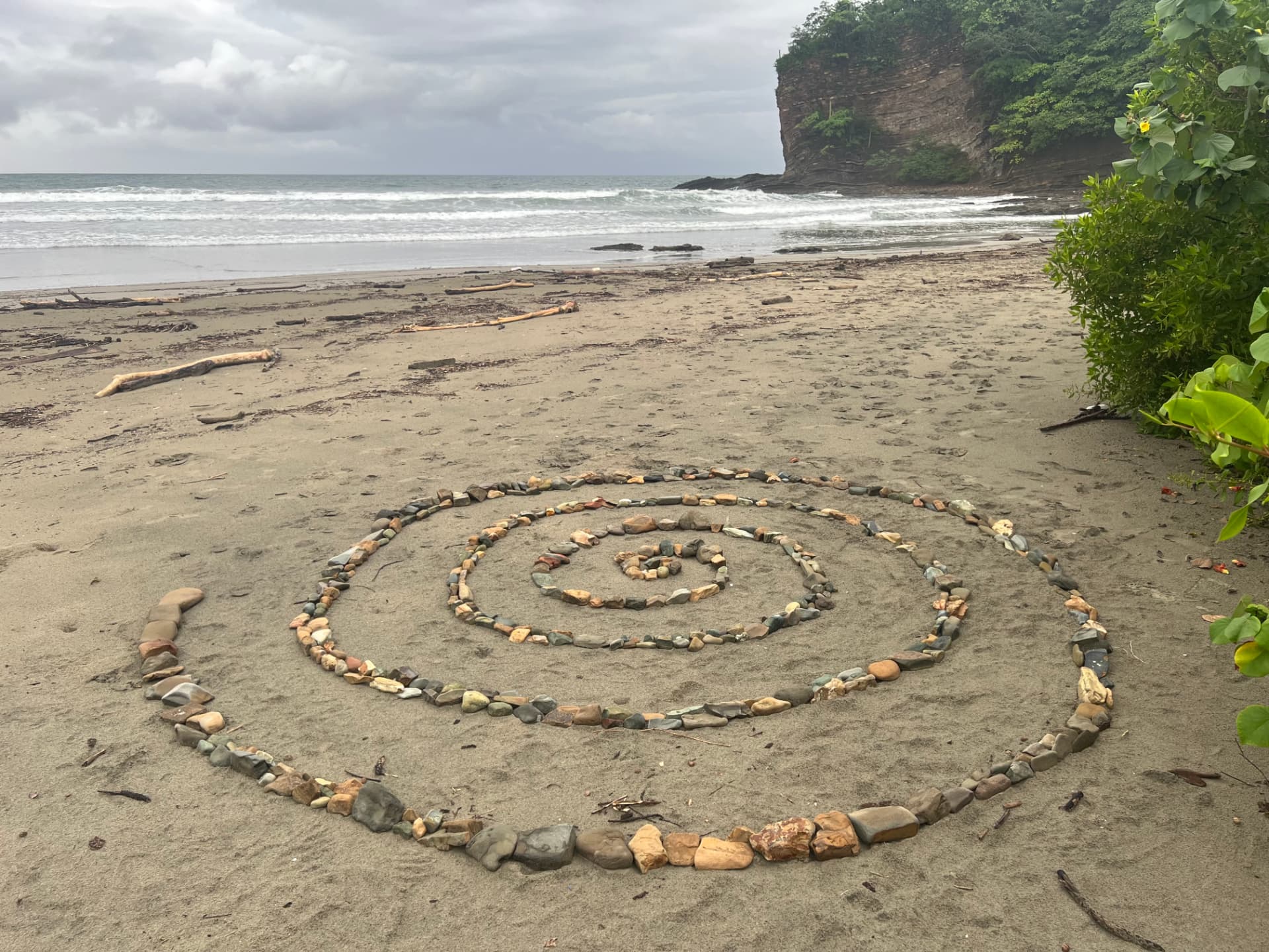 A ceremonial spiral of colorful stones arranged on the sand at Playa El Coco